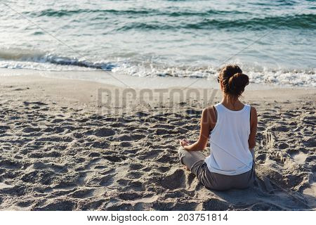 Young woman practicing yoga on the beach.