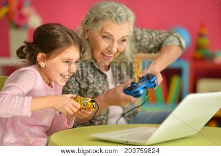 Grandmother and granddaughter playing computer games on laptop