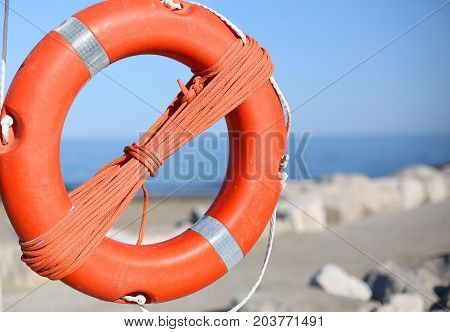 Orange Lifebuoy For People Near Rocks At The Sea