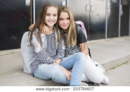 Portrait of two pre teenage girls studying outdoors in school yard