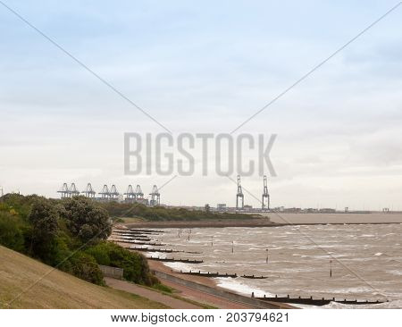 Sea Industry Cargo And Shipping Cranes In The Distance Beach Groynes Harwich Port
