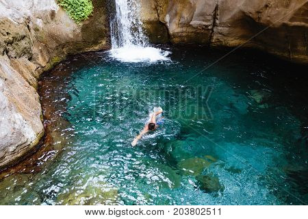Man swimming in turquoise and crystal clear water near small waterfall in Sapadere canyon near Alanya of Turkey