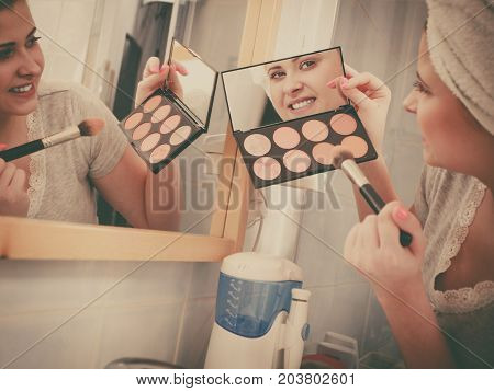 Woman In Bathroom Applying Contour Bronzer On Brush