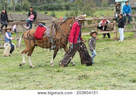 June 3 2017 Machachi Ecuador: a child and a cowboy walking with a horse outdoors in the Andean town