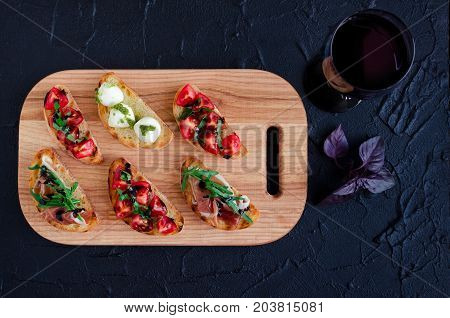 Brushetta set for wine. Variety of small sandwiches served with glass of red wine. Delicious snack appetizer antipasti on party or picnic time. Italian cuisine concept. Slow living. Top view.
