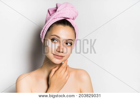Young beautiful woman after bathing with a towel on her head, looking after the skin, looking with interest to the left