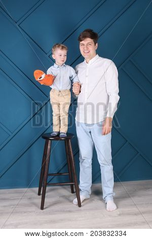 Young handsome father and little son on stool pose in blue studio