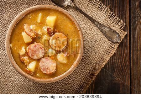 Wooden Bowl Of Split Pea Soup With Sausage And Potatoes