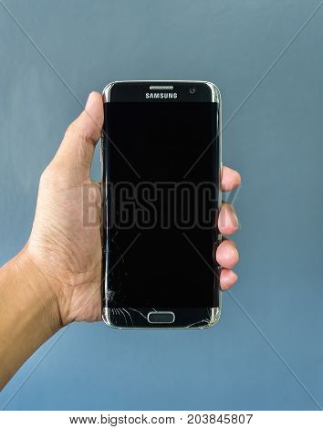 Chiangrai Thailand: September 2 2017 - Human hand holding broken Samsung Galaxy S7 edge smartphone