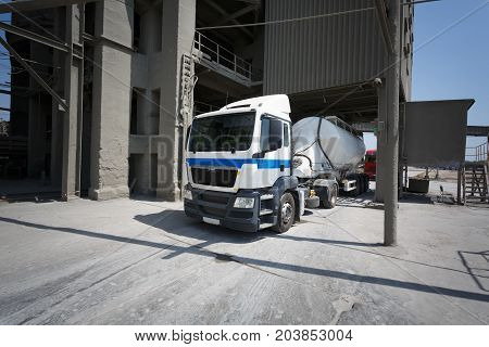 White truck driving along the asphalt road around the factory. Big metal fuel tankers shipping fuel. The truck left the parking lot at the factory. Truck way.