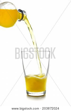 pouring yellow softdrink lemonade made from orange juice from a bottle into a glass isolated on a white background vertical