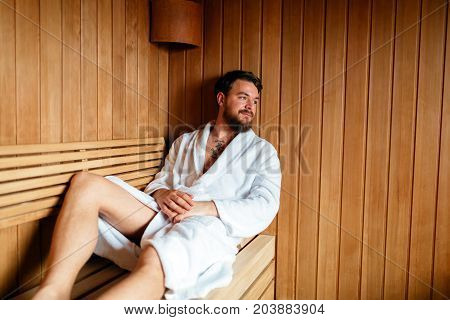 Handsome man relaxing in sauna and staying healthy