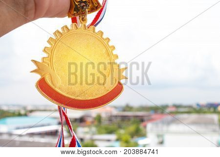 Winner hand holding golden medals to blur building background for show team success with their business Champion and Awards Concept