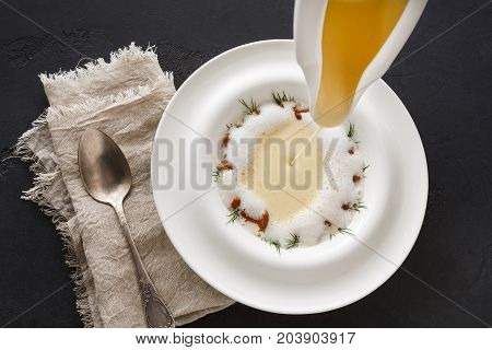 Pouring broth to mushroom cream soup top view. Original restaurant serving of delicacy meal, copy space