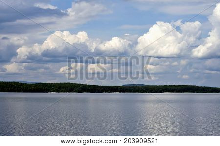 bright clouds reflected in the water South Ural lake Uvildy in the distance are seen the Ural mountains