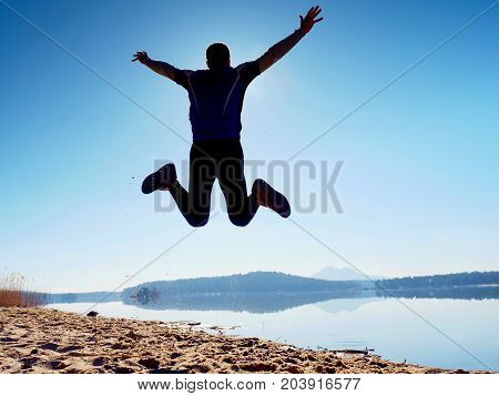 Jumping Man. Sportsman Crazy Jumping  And Jogging On Beach During The Sunrise