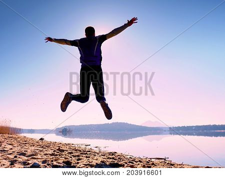 Jumping Man. Sportsman Crazy Jumping  And Jogging On Beach During The Sunrise