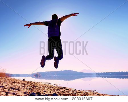 Jumping Man. Sportsman Crazy Jumping  And Jogging On Beach During The Sunrise