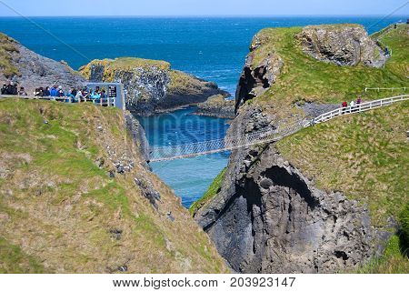 Ballintoy, United Kingdom - May 2, 2016: Carrick-a-Rede Rope Bridge, a popular tourist destination in Northern Ireland. Tourists passing the bridge.