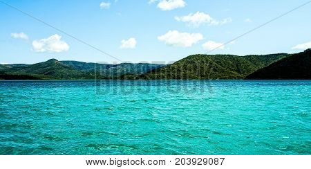 Tropical Paradise - Marinescape. This Island Head anchorage is postcard stuff with crystal clear turquoise water bold heavily timbered hills in the foreground with vivid distant mountains as a backdrop.