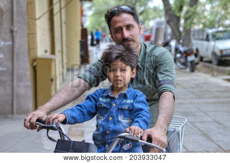 Fars Province Shiraz Iran - 18 april 2017: A family of two people a father and a boy about 5 years old ride a motorbike along a city street.
