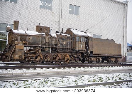 Old rusty abandoned steam engine on railroad in winter