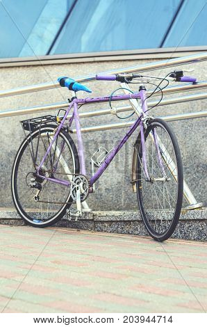 Old road bike of pink color with a ridiculous seat rewound blue electrical tape. Cycling or commuting in city urban environment ecological transportation concept