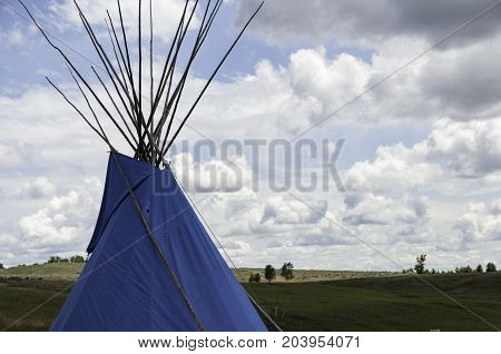 blue teepee in Montana with fluffy clouds in the sky
