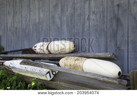 old wooden buoy floats laying against a wood shed