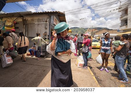 April 13 2017 Ibarra Ecuador: a woman walks with plastic bowl on her head as sun protection