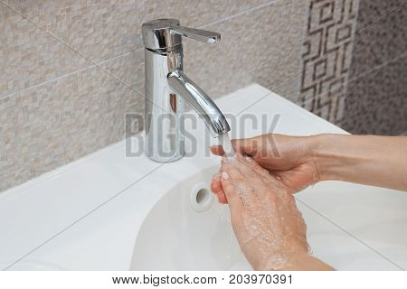 Washing of hands with soap under running water.