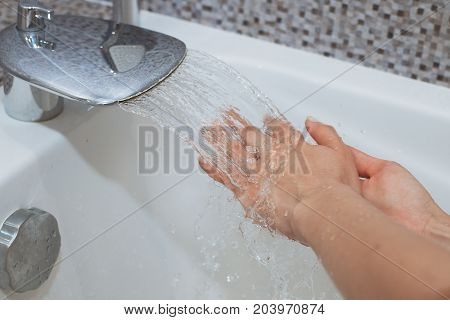 Washing of hands with soap under running water.
