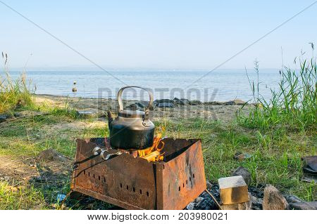 Bloated teakettle on a fire at a bank of a lake - hiking landscape,  Uveldy, The Urals, Russia