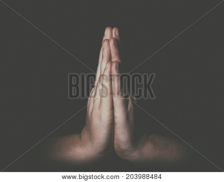 Man hands in praying position low key image