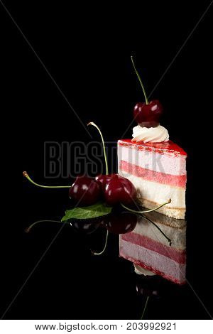 Sweet cherry cake with cherries isolated on black background with reflection.