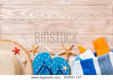 Flip Flops, Straw Hat, Starfish, Sunscreen Bottle, Body Lotion Spray On Wooden Background Top View .
