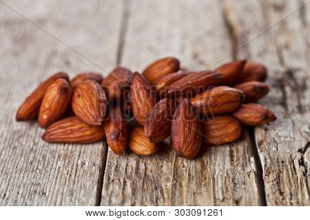 Pile of fresh organic almond seeds on rustick wooden table background.