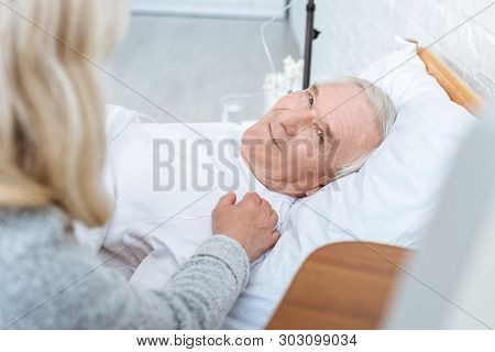 Partial View Of Senior Woman And Smiling Ill Man In Clinic