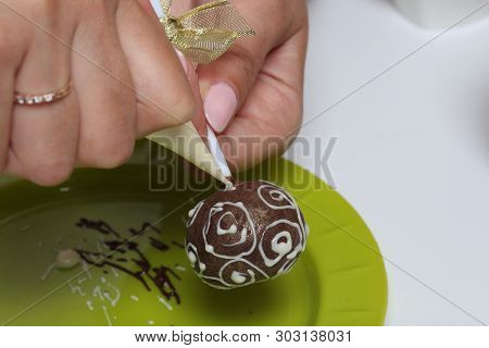 A Woman Decorates With The Help Of White Chocolate Popcake Glazed With Dark Chocolate.