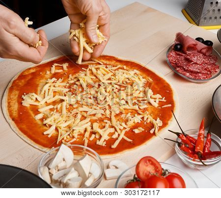 Chef Spreading Cheese Toppings On Pizza Base, Closeup, Crop