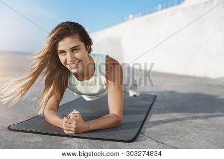 Motivated Attractive Healthy Caucasian Sportswoman Smiling During Plank Strenghths Exercise, Doing F