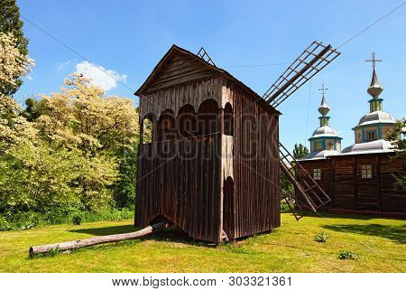 Stunning Landscape View Of Wooden Ancient Windmill And Typical Wooden Church. Pereyaslav-khmelnitsky