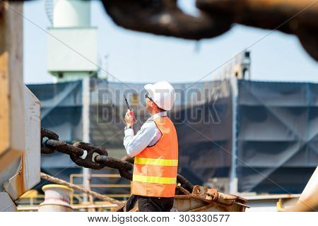 Foreman Using Walkie-talkie And Safety Helmet To Work In Cargo Ship