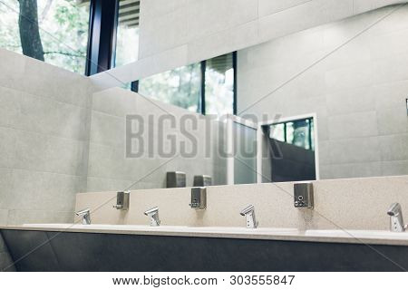 Modern Interior Design In Public Toilet. New Sinks, Taps With Mirror And Window Above
