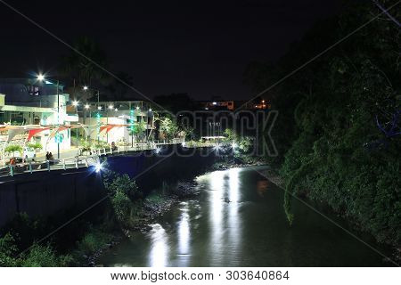 Tourist Area Walkaway Next To Tropical River And Forest That Is Brightly Lid With Neon Lights