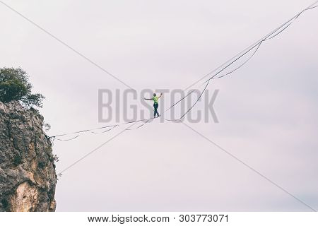 Highline On The Background Of The Mountains Makes A Step. A Man Is Walking Along A Stretched Sling. 