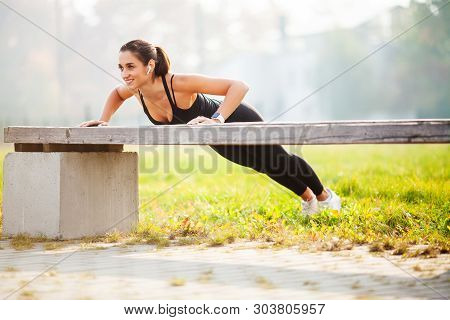 Portrait Of Beautiful Sporty Woman 20s In Sportswear Doing Push-ups, And Listening To Music With Blu