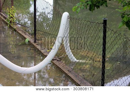Large Diameter Plastic Water Hose Connected To Strong Water Pump Over Wire Fence Used To Pump Flood 