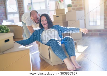 Funny and crazy couple having fun riding a cardboad box as a car, smiling happy and lauging at new home