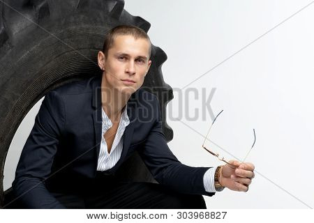 Attractive Young Man With Short Haircut Wearing Black Suit, Holding Sunglesses In Hand, Looking At T